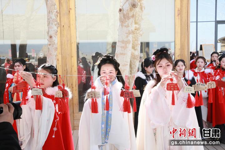 图为身着汉服的小姐姐们在祈福长廊悬挂祈福牌。